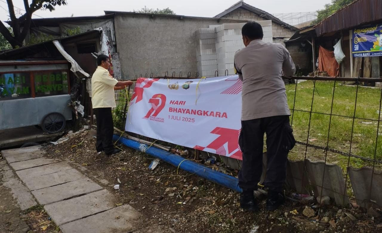 Bhabinkamtibmas Pasang Spanduk HUT Bhayangkara ke-79 Bersama Petugas Keamanan