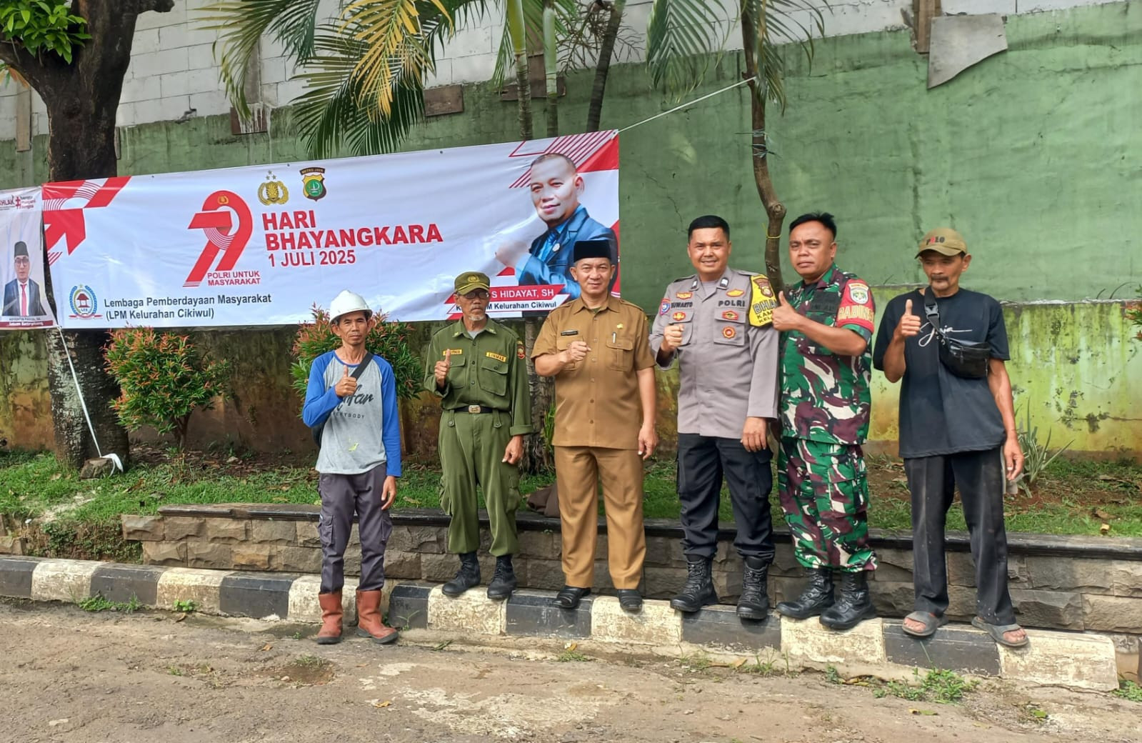 Sinergitas Tiga Pilar Pasang Spanduk HUT Bhayangkara ke-79 Kelurahan Cikiwul
