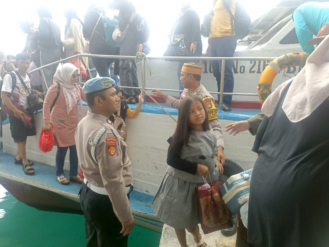 Polisi Humanis Polsek Kepulauan Seribu Utara Bantu Penumpang Turun dari Kapal di Dermaga Pulau Harapan
