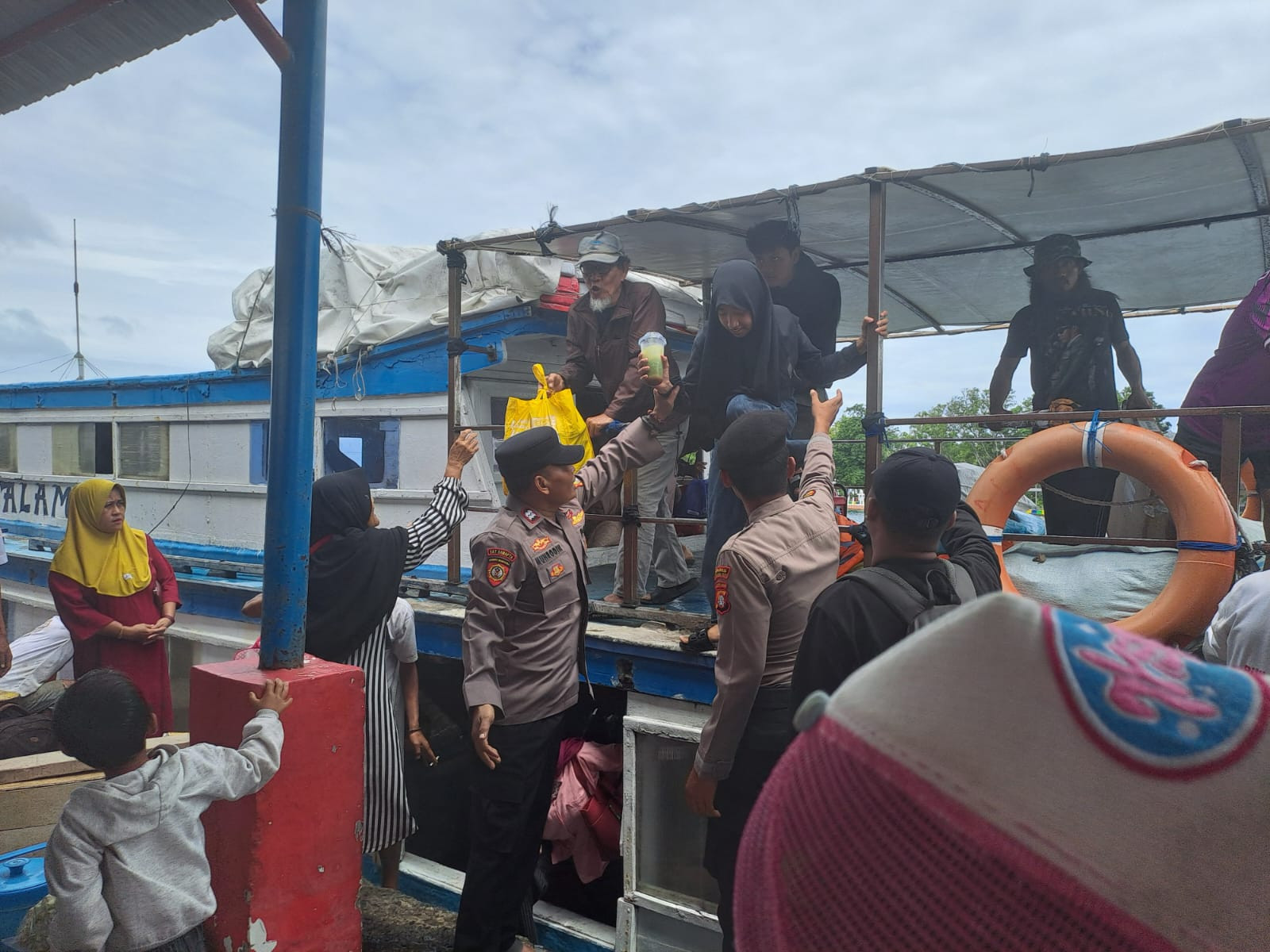 Polisi Baik Polsek Kepulauan Seribu Utara Bantu Penumpang Turun dari Kapal di Dermaga Pulau Panggang