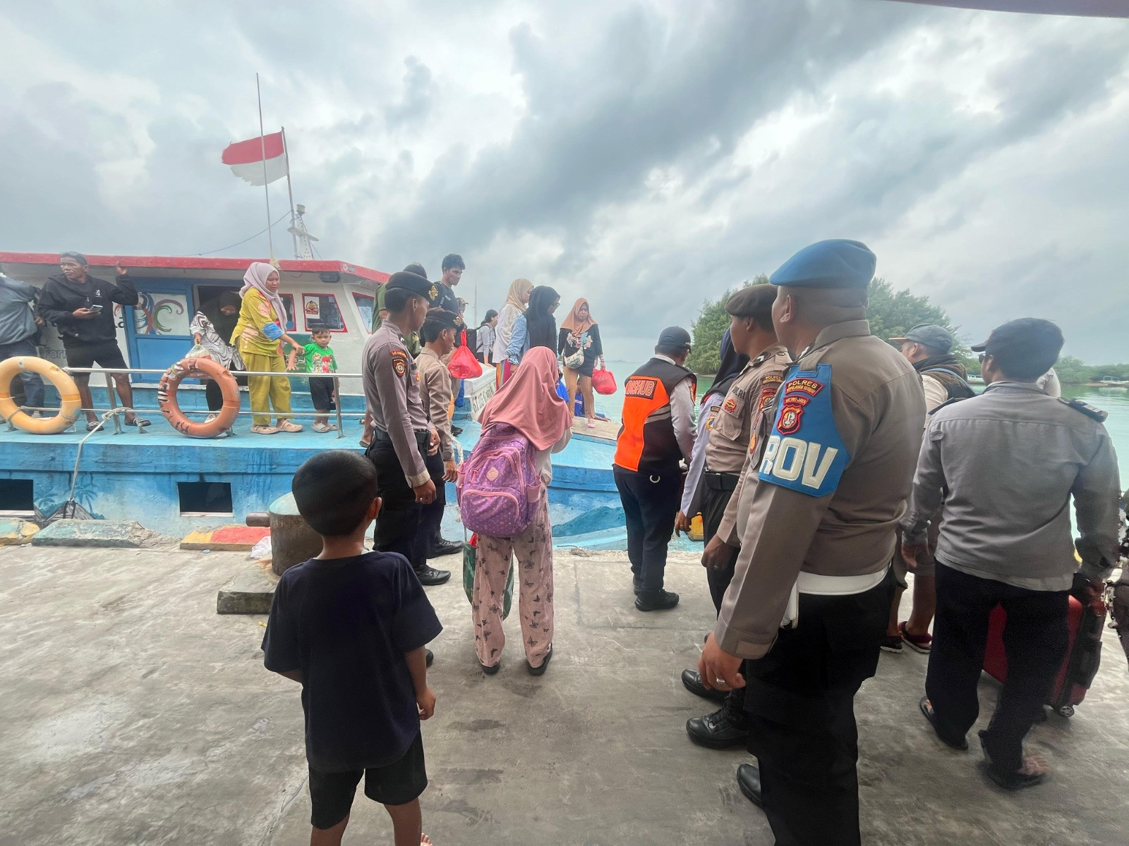 Polisi Baik Polsek Kepulauan Seribu Utara Bantu Penumpang Turun Kapal di Dermaga Pulau Kelapa